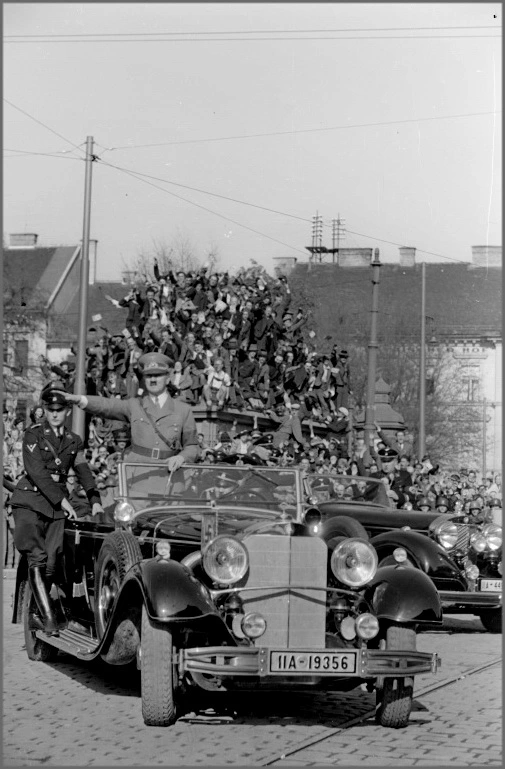 Das Foto zeigt Adolf Hitler mit ausgestrecktem rechen Arm im Auto stehend durch Graz fahren.