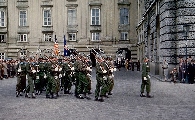 US-Soldaten bei der Wachablöse am Heldenplatz. Farbfoto einer Gruppe US-Soldaten die mit Gewehren und weißen Handschuhen marschieren. Schaulustige Bevölkerung ist zu sehen.