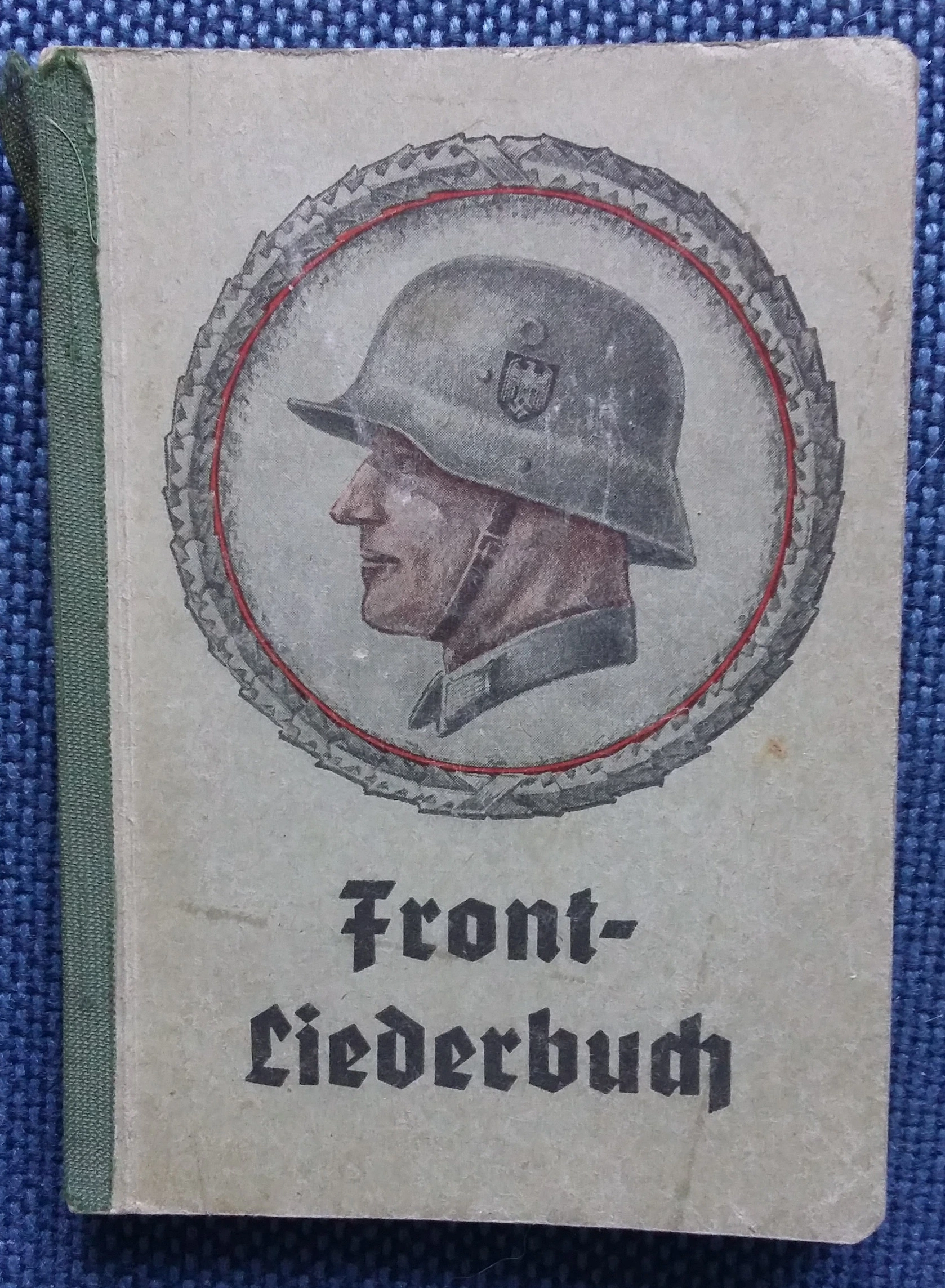 Cover mit Soldatenkopf im Profil mit Stahlhelm in Eichenlaubkreis. Darunter: "Front- Liederbuch"