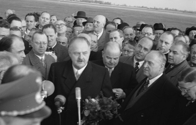 Menschenmenge um die Politiker stehend, die selbst vor einem Mikrofon stehen.te