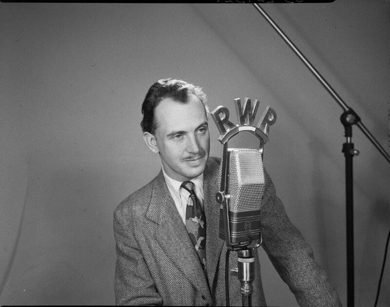 Fred Ziller Portrait in Anzug mit Kravatte vor dem RWR-Mikrofon.