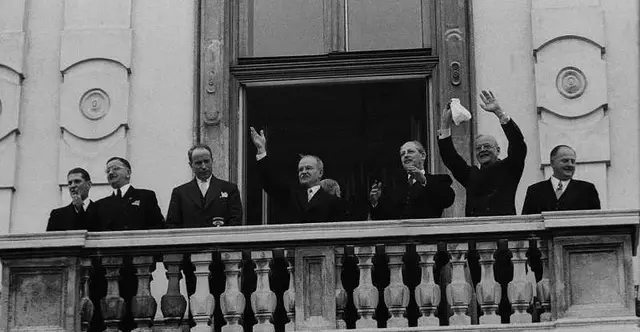 Uhr Politiker in schwarzen Anzügen teilweise herunterwinkend. - Die Politiker zeigen sich der im Belvederepark wartenden Menge und grüßen vom Balkon: (von links nach rechts) der französische Botschafter Roger Lalouette, Außenminister Leopold Figl, Antoine Pinay (französischer Außenminister), Wjatscheslaw Molotow (sowjetischer Außenminister), Harold Macmillan (britischer Außenminister), US-Außenminister John Foster Dulles und Bundeskanzler Julius Raab.