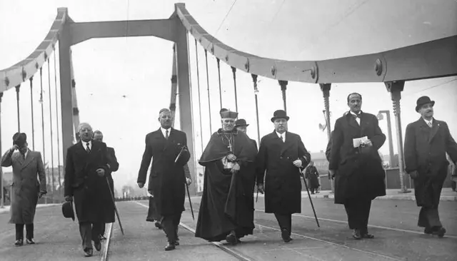 Eröffnung der Wiener Reichsbrücke. In der Mitte Bundeskanzler Kurt Schuschnigg, Kardinal Theodor Innitzer und Bundespräsident Wilhelm Miklas mit Melone. Wien, am 10. Oktober 1937. Die Herrschaften gehen nebeneinander über die Brücke.