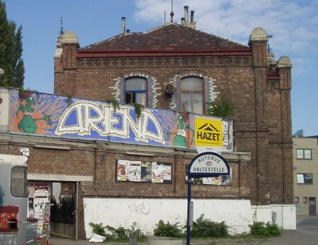 Arena: Backsteingebäude und Backsteinmauer mit aufgemalter Aufschrift "Arena".