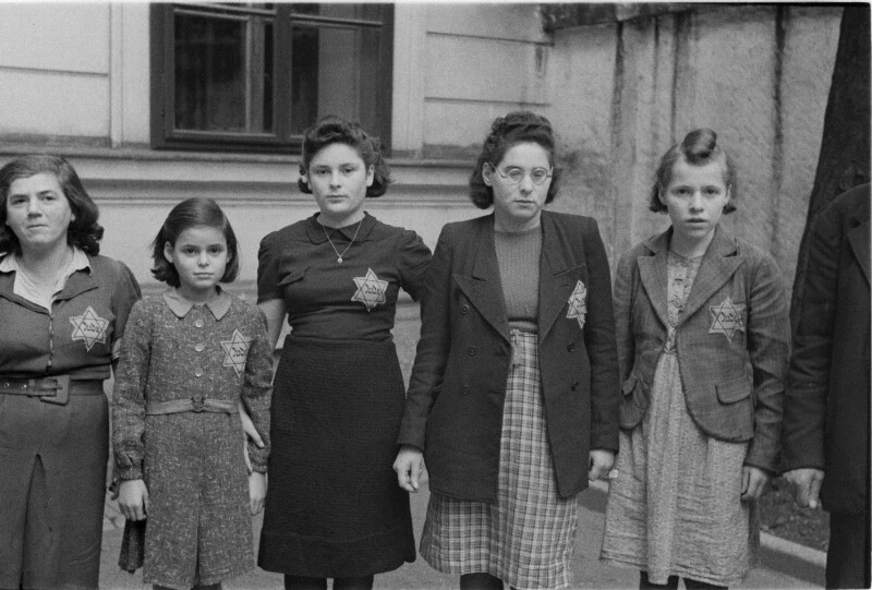 Die jüdische Bevölkerung wird gezwungen einen Judenstern zu tragen. Wien 1941. Fünf Frauen und Mädchen mit Judenstern auf der linken Brust in einem Hinterhof in Wien fotografiert.