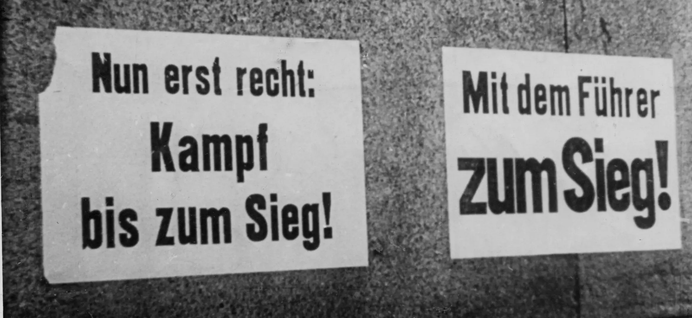 Propagandaplakate an Häuserwänden: "Nun erst recht: Kampf bis zum Sieg!" "Mit dem Führer zum Sieg!" 