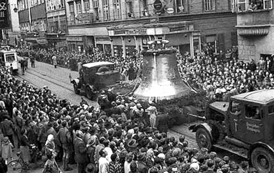 Die Pummerin fährt auf dem Tieflader durch die Linzer Landstraße, 25. April 1952. Viele Schaulustige am Straßenrand in der Stadt Linz.