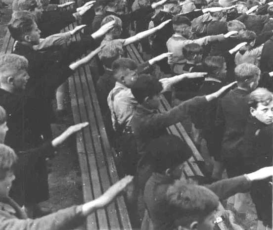 Feierliche Aufnahme der zehnjährigen Mädchen und Buben ins Deutsche Jungvolk (DJ), die Kinderorganisation der Hitlerjugend. Hier beim Absingen des Liedes der HJ. 19. April 1943. Ort unbekannt. Burschen in einem Stadion beim Hitlergruß.