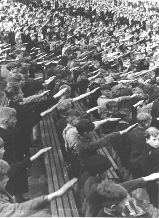 Feierliche Aufnahme der zehnjährigen Mädchen und Buben ins Deutsche Jungvolk (DJ), die Kinderorganisation der Hitlerjugend. Hier beim Absingen des Liedes der HJ. 19. April 1943. Ort unbekannt. Burschen in einem Stadion beim Hitlergruß.